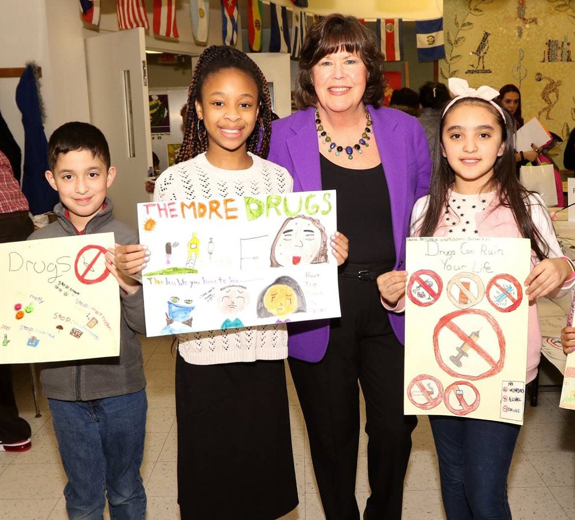 Ginger with students holding artwork